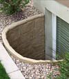 A durable plastic egress window well installed in a rock garden in Queens.