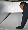 A contractor installing TerraBlock™ floor insulation in a Elmhurst crawl space