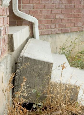 sinking outdoor concrete steps showing cracking and soil washout in Rego Park
