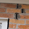 A brick wall displaying stair-step cracks and messy tuckpointing on a Manhattan home