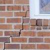 long jagged cracks starting at the corner of a window along a brick wall on a Fresh Meadows home