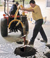 Digging a hole in the garage floor to make room for a wall anchor installation in Maspeth, New York