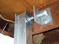 Securing the i-beam system to the top of the floor joist in a foundation wall repair in Elmhurst.