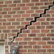 stair step cracking reaching from a window along the foundation wall in Bronx