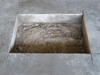 Creating the hole in the garage slab floor during the wall anchor installation in South Richmond Hills.