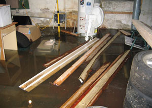 A severely flooding basement in Elmhurst, with lumber and personal items floating in a foot of water