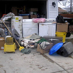 Soaked, wet personal items sitting in a driveway, including a washer and dryer in Astoria.