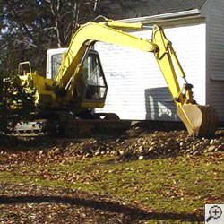 A backhoe excavating a foundation to install an exterior perimeter weeping tile drainage system in Calhoun.