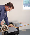 installing a waterproof vapor barrier on a basement floor to prepare for basement carpeting in a Manhattan home