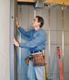 Insulated basement wall panels being placed against a concrete foundation wall in Queens
